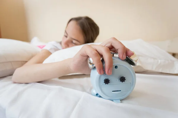 Närbild bild av sovande ung flicka håller handen på väckarklocka — Stockfoto
