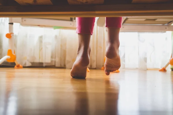 Imagen de cerca tonificada de la joven descalza en pijama de pie sobre piso de madera en el dormitorio —  Fotos de Stock