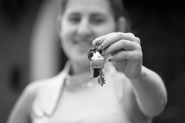 Closeup black and white portrait of smiling young woman holding keys from new house — Stock Photo, Image