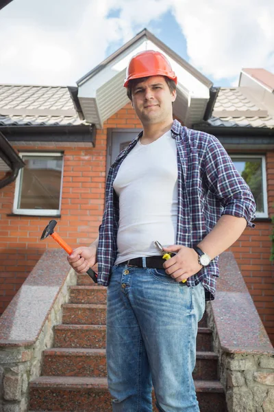 Portret van lachende jonge reparateur poseren met de hulpmiddelen op de huisdeur — Stockfoto