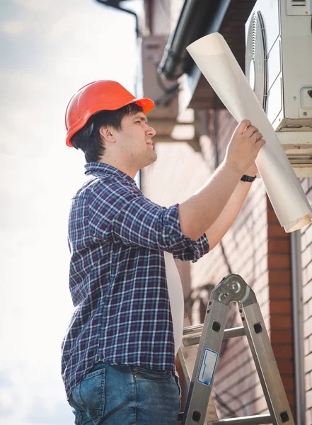 Portret van mannelijke ingenieur op zoek blauwdrukken van huis airconditioningsysteem — Stockfoto