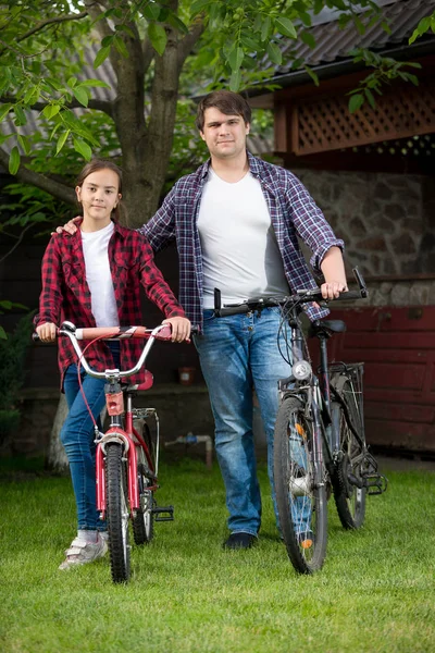 Heureux jeune père avec fille marchant avec des bicyclettes à la maison arrière-cour — Photo