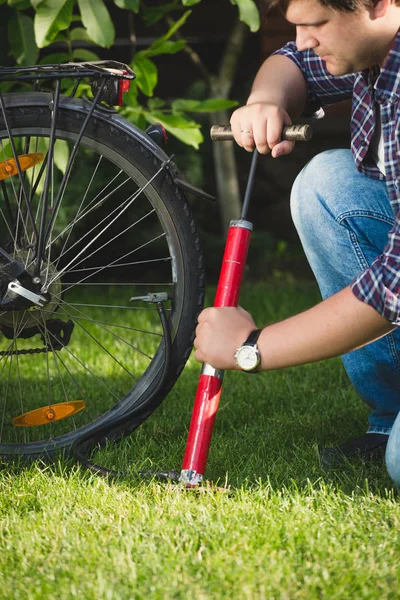 Imagen de primer plano del joven que utiliza la bomba de aire para fijar el neumático plano de la bicicleta — Foto de Stock