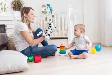 Yürümeye başlayan çocuk oğlu ile oynarken el kukla oyuncak giyen genç gülümseyen kadın