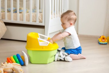 katta oturan ve plastik tuvalet pot oynayan 10 aylık yürümeye başlayan çocuk