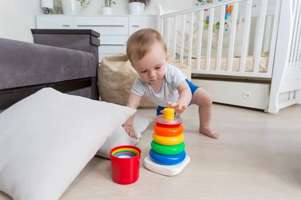 Bedårande 10 månader gamla barn pojke sitter på golvet och bygga leksak torn — Stockfoto