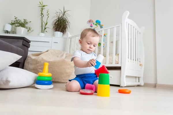 Skoncentrowany maluch śliczny chłopiec siedzi na podłodze i zbudowanie wieży zabawka — Zdjęcie stockowe