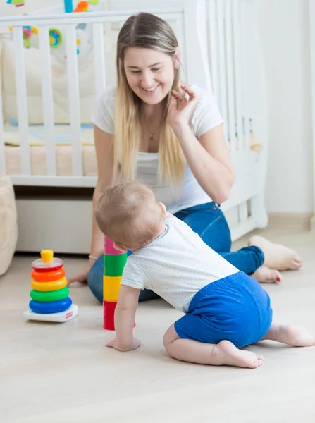 Glad ung mamma leker med hennes barn son på golvet — Stockfoto