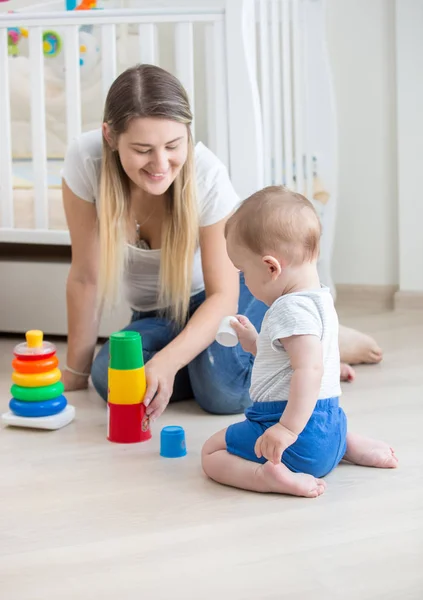Gyönyörű fiatal nő ül a 10 hónapos fia, és játék-val toys — Stock Fotó
