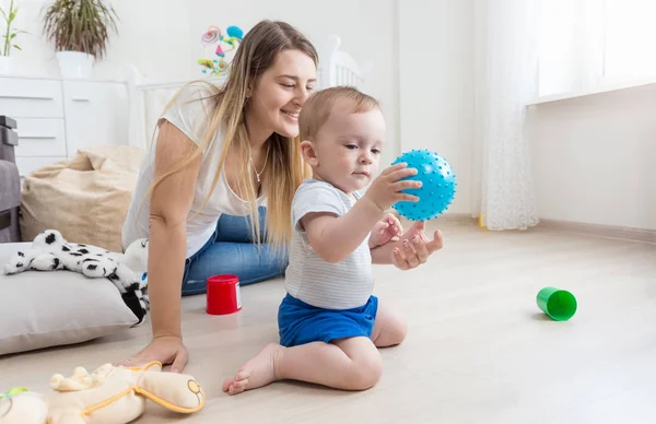 Entzückender 10 Monate alter Junge spielt mit blauem Ball auf dem Fußboden im Schlafzimmer — Stockfoto