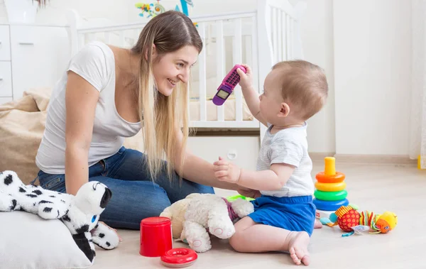 10 mesi bambino ragazzo mostrando giocattolo cellulare a sua madre — Foto Stock