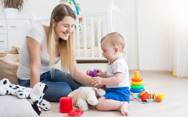 Mujer joven sonriente con su hijo pequeño jugando con el teléfono móvil de juguete —  Fotos de Stock