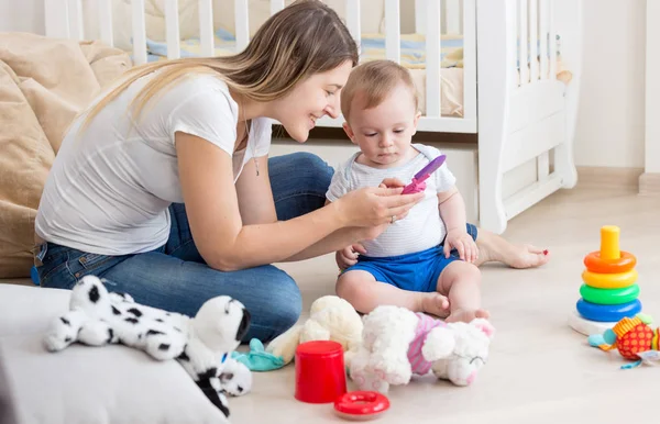 Szczęśliwy uśmiechający się matka jej chłopiec dziecko uczy się korzystania z telefonu komórkowego — Zdjęcie stockowe