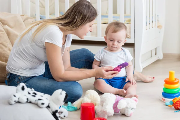 Piękna młoda kobieta gra z jej 10 miesięcy toddler chłopiec i uczy się korzystania z telefonu komórkowego — Zdjęcie stockowe