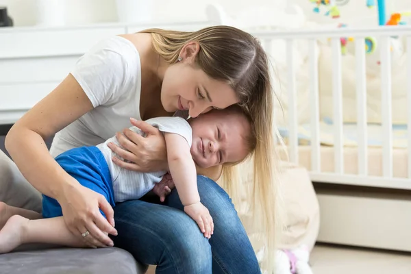 Retrato de una joven madre cariñosa abrazando y calmando a su bebé llorando —  Fotos de Stock