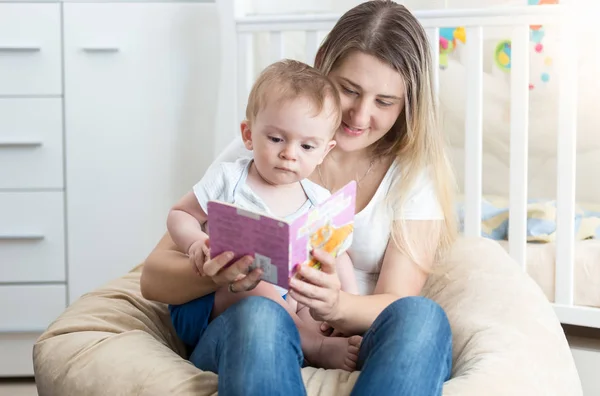 Adorable 10 months old toddler boy sitting on mother lap and listening to fairytale — Stock Photo, Image