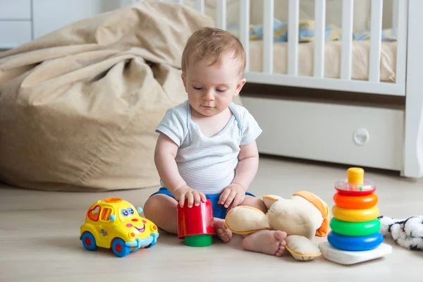 10 miesięcy toddler chłopiec siedzi na podłodze i bawi się zabawkami — Zdjęcie stockowe