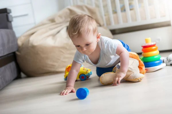 Adorable niño pequeño arrastrándose en el suelo y jugando con juguetes —  Fotos de Stock
