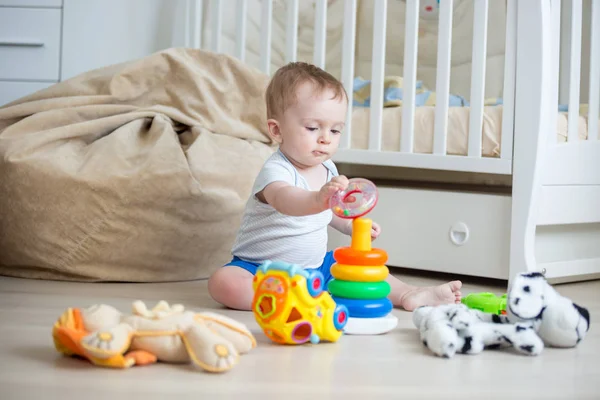 Adorable toddler boy sitting on floor and building colorful toy tower — Stock Photo, Image