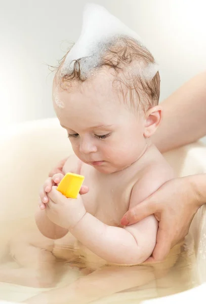 Portrait of cute 10 months old baby boy playing in small plastic bathtub — Stock Photo, Image