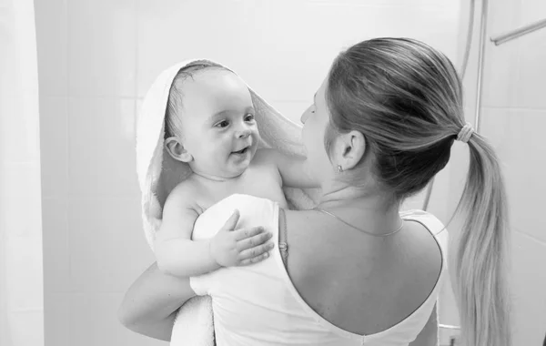 Portrait noir et blanc de bébé garçon souriant couvert de serviette regardant la mère après avoir pris un bain — Photo