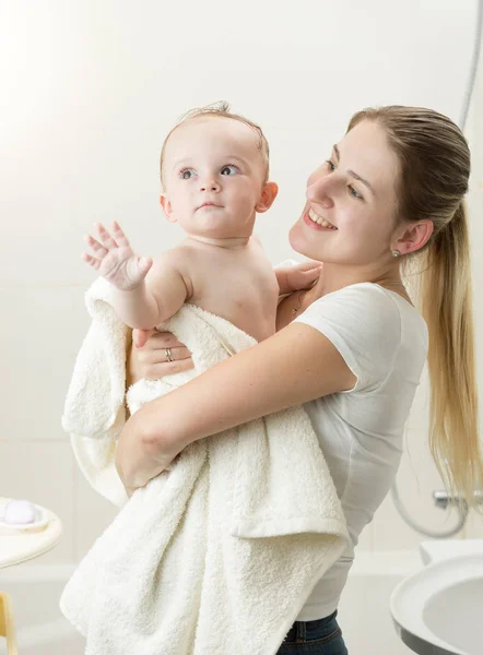 Onun erkek bebek tutan genç gülümseyen kadın havlu banyo sonra kaplı. — Stok fotoğraf