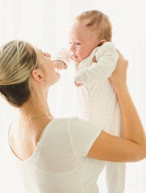 Holding ve 3 aylık bebeğini seyir mutlu genç anne portresi