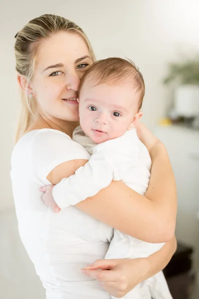 Porträt einer lächelnden jungen Mutter, die ihren 3 Monate alten Jungen umarmt — Stockfoto