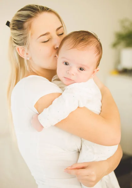 Retrato de feliz jovem mulher abraçando e beijando seu bebê bonito — Fotografia de Stock