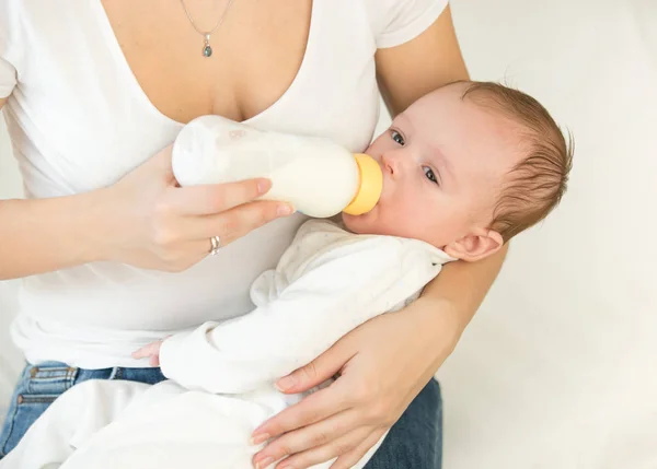 Retrato de un bebé de 3 meses bebiendo leche del biberón en el regazo de las madres — Foto de Stock