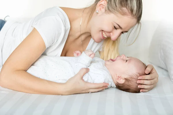 Porträt eines lachenden 3 Monate alten Jungen und einer jungen Frau, die auf dem Bett liegen — Stockfoto