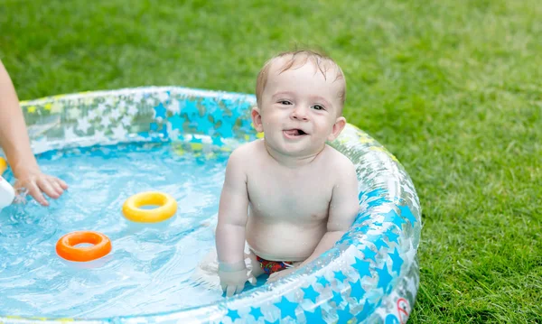 Divertente ritratto di un bambino sorridente che nuota nella piscina gonfiabile nel cortile — Foto Stock