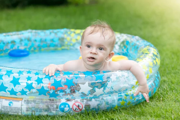 Retrato de niño adorable acostado en la piscina inflable en el patio trasero de la casa — Foto de Stock