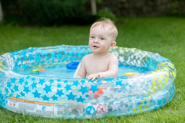 Ritratto di bambino allegro che si gode il nuoto nella piscina gonfiabile — Foto Stock