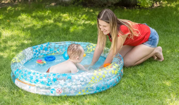 Feliz mujer sonriente jugando con su bebé de 10 meses en la piscina inflable — Foto de Stock