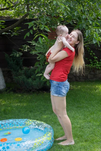 Feliz madre joven sacando a su hijo de la piscina inflable — Foto de Stock