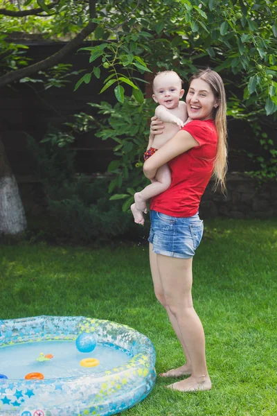 Retrato de feliz madre risueño con bebé niño después de nadar en piscina inflable —  Fotos de Stock
