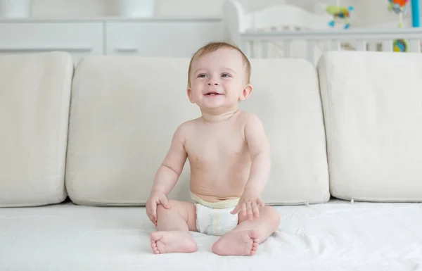 거실에서 소파에 앉아 밝은 웃는 아기 — 스톡 사진