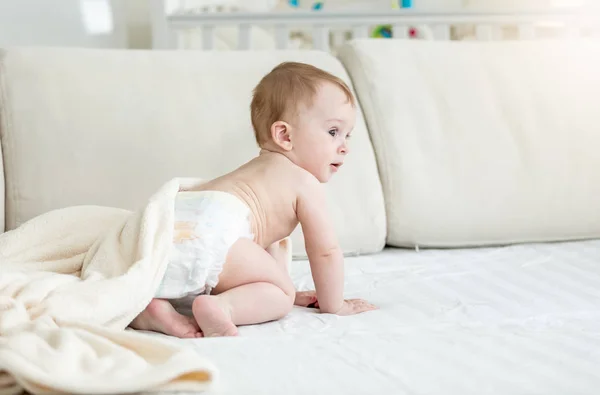 Bedårande 10 månader gammal pojke i blöjorna sitter på soffa — Stockfoto