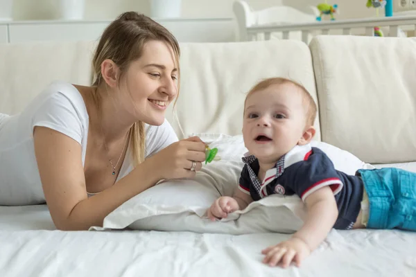 Retrato de una joven madre sonriente con su bebé acostado en la cama —  Fotos de Stock