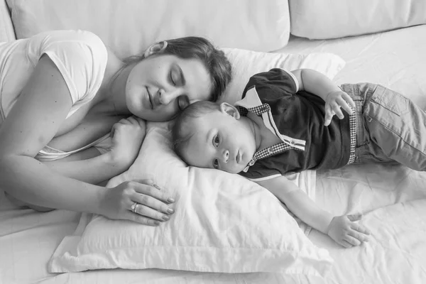 Noir et blanc vue haute photo de la jeune mère dormant à côté de son bébé garçon couché dans son lit — Photo