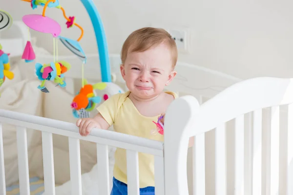 Portriat de niño de 10 meses parado en una cuna llorando —  Fotos de Stock