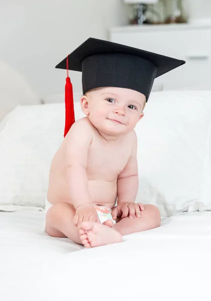 Porträt des niedlichen lächelnden Kleinkindes mit Universitätsabschlussmütze, das in die Kamera blickt — Stockfoto