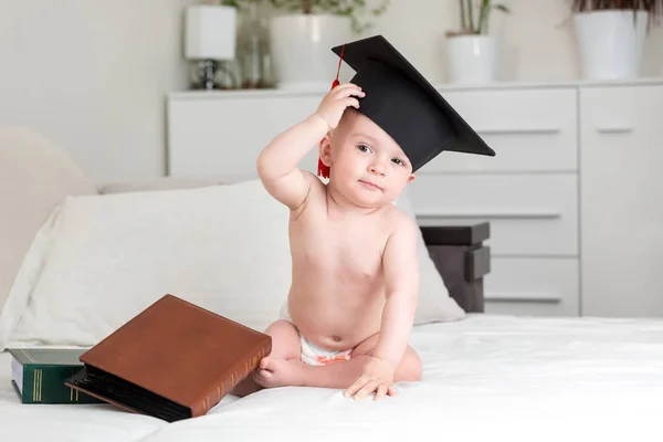 Carino bambino genio bambino in berretto laurea universitaria sfregamento fronte e guardando in macchina fotografica. Concetto di educazione precoce dei bambini — Foto Stock