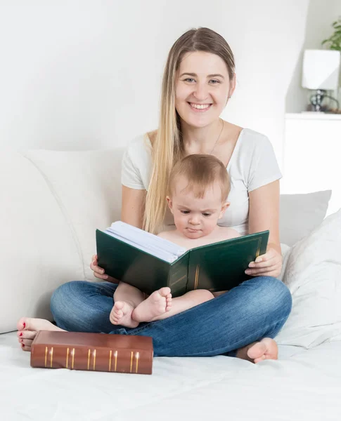 Retrato de menino bonito sentado no colo das mães e lendo grande livro — Fotografia de Stock