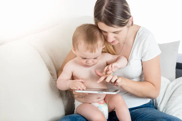 Portret van 1 jaar oude babyjongen zit op moeders schoot en het gebruik van digitale tablet — Stockfoto
