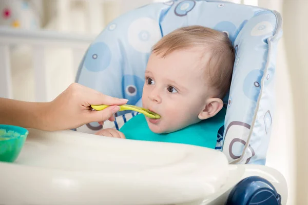 Closeup portrait of cute baby boy eating fruit sauce from spoon Royalty Free Stock Images