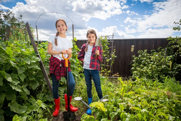 Due ragazze adolescenti in posa in giardino con attrezzi da giardinaggio — Foto Stock