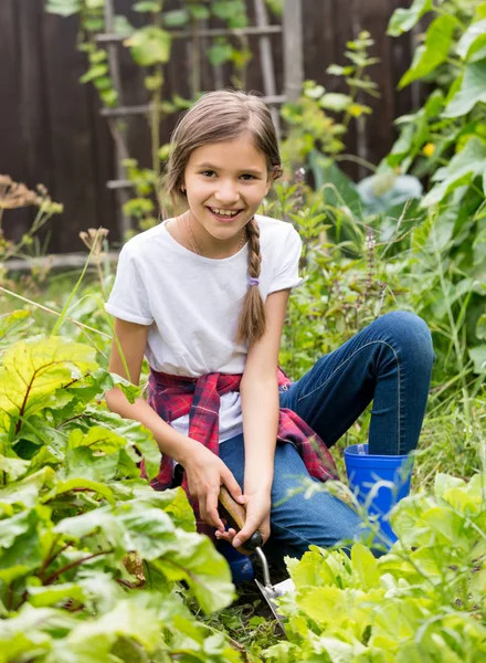 Portré, szép mosolygó tizenéves lány ül a kertben, és kerti ágy spudding — Stock Fotó
