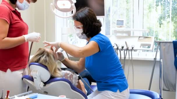 4 k footage dentysta z pielęgniarka leczenia pacjent siedzi w Fotel dentystyczny — Wideo stockowe